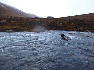 Ian Fitz crossing the swollen Fords of A'an. The emergency shelter in the background.